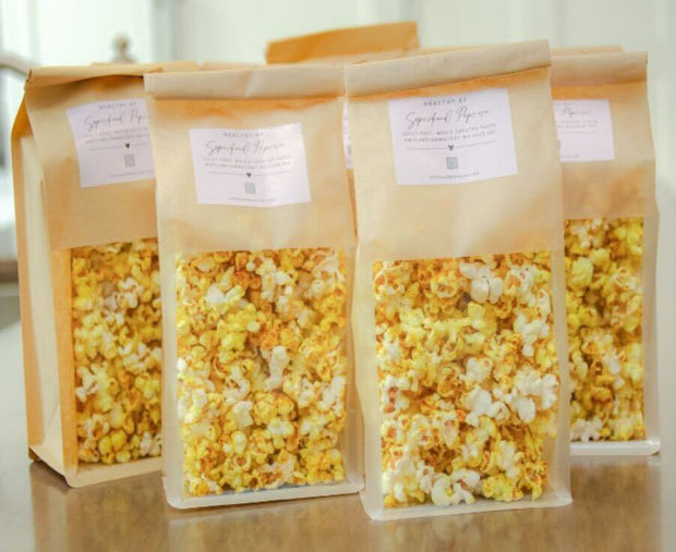 Four bags of popcorn with visible popcorn inside on a light background